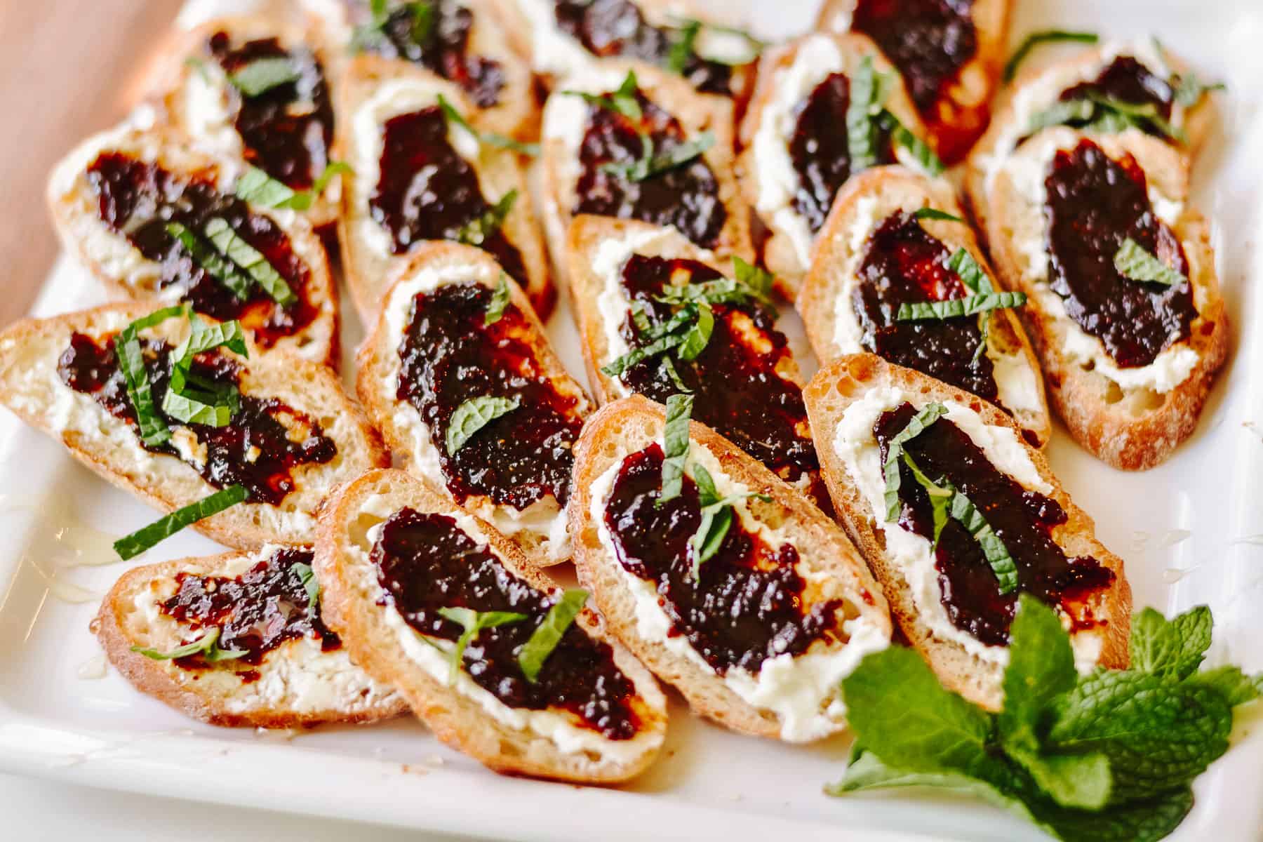 Plate full of crostini with goat cheese and jam.