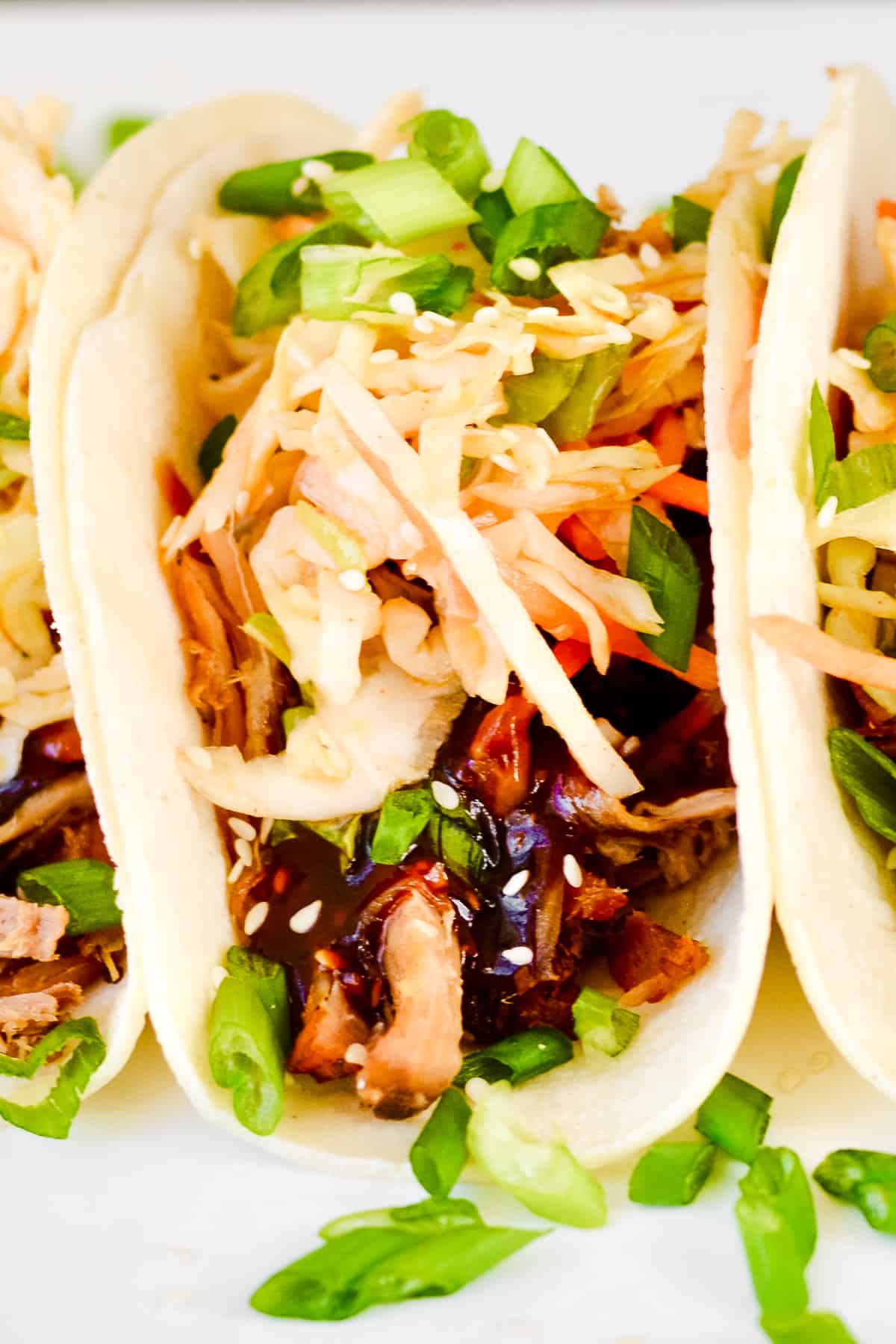 Close up of Korean BBQ tacos with pulled pork, quick kimchi and green onion.