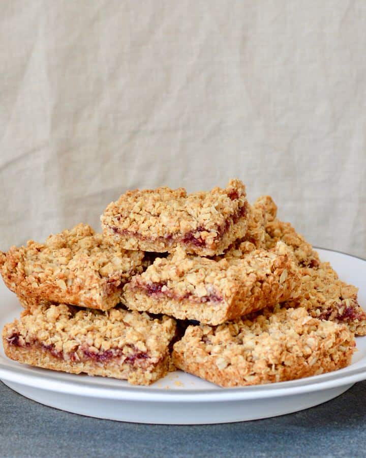 Berry Oat Bars with No Refined Sugar. Simple recipe, ready in less than 30 minutes. Raspberry preserves tucked inside layers of crumbly oat mixture. Perfect for breakfast or dessert!