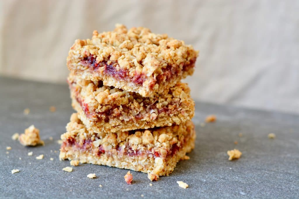 Berry Oat Bars with No Refined Sugar. Simple recipe, ready in less than 30 minutes. Raspberry preserves tucked inside layers of crumbly oat mixture. Perfect for breakfast or dessert!