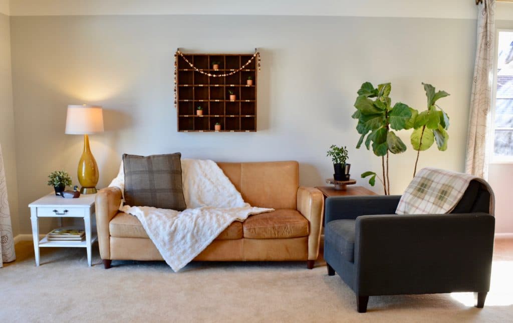 Airbnb rental ideas and checklist for renting your primary residence or home. Living space with brown leather couch and fiddle leaf fig. 