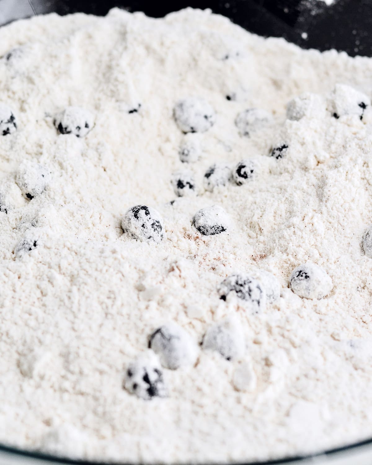 Blueberries mixed in with flour in a bowl.
