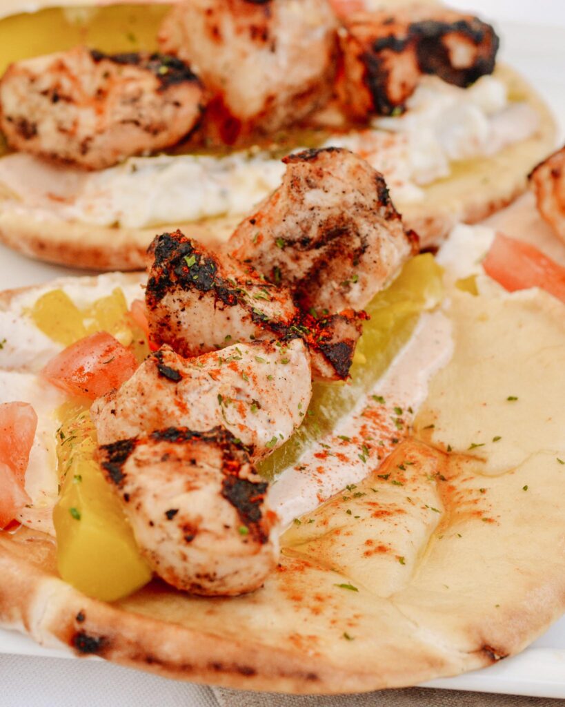 Chicken Tawook Pita Sandwich - Lebanese flavors with grilled chicken, perfectly spiced marinade and sauces, along with tomatoes, pickles and packed with tons of authentic, but easy flavor. #tawook #lebanese #chickendinner