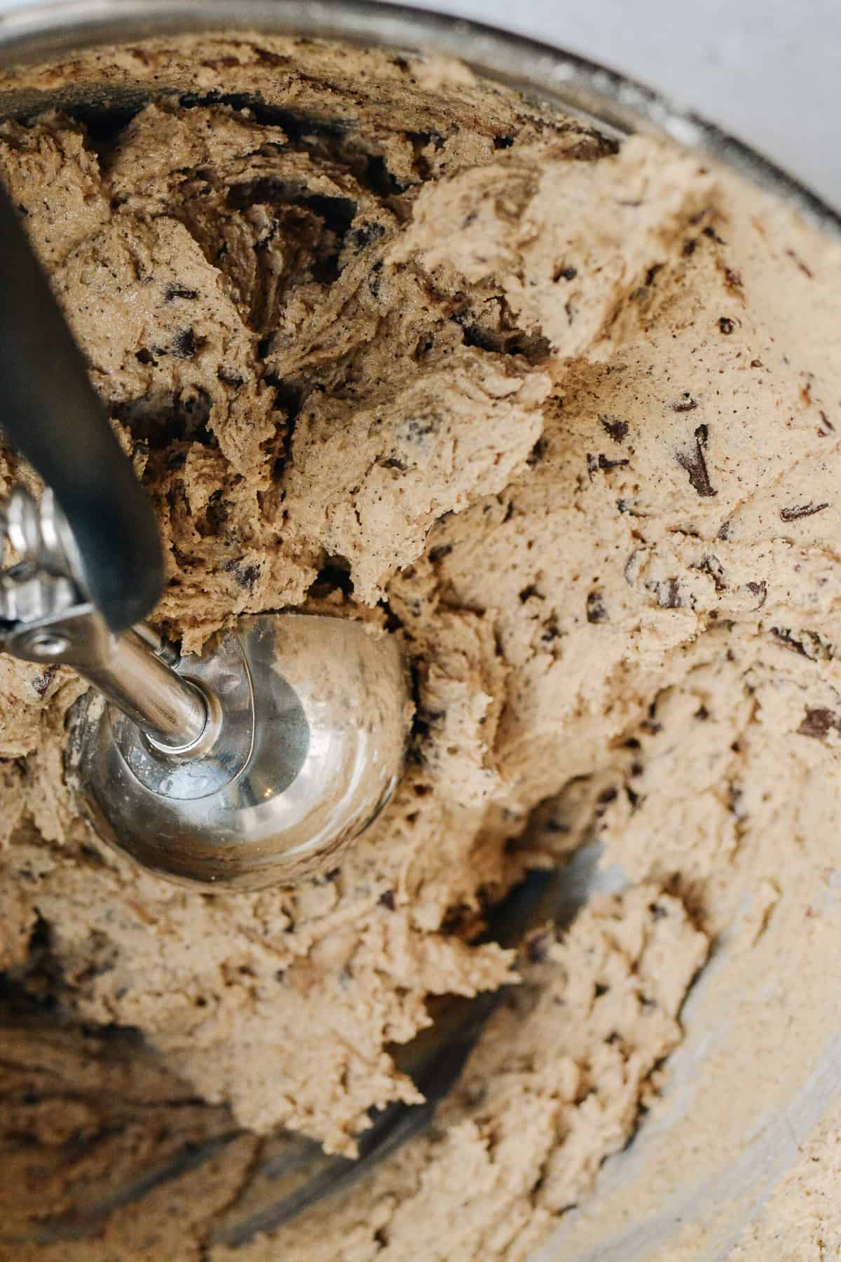 Cookie batter in a bowl with a cookie scoop.