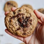 Hand holding an espresso cookie with more cookies in background.