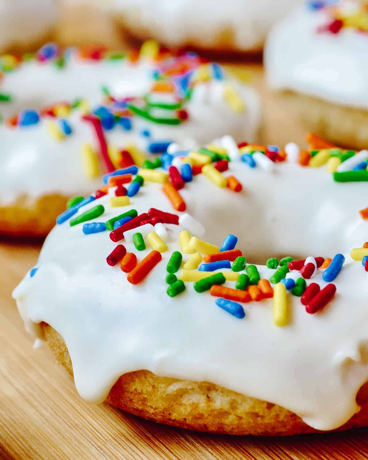 Close up of vanilla donut with white frosting and sprinkles.