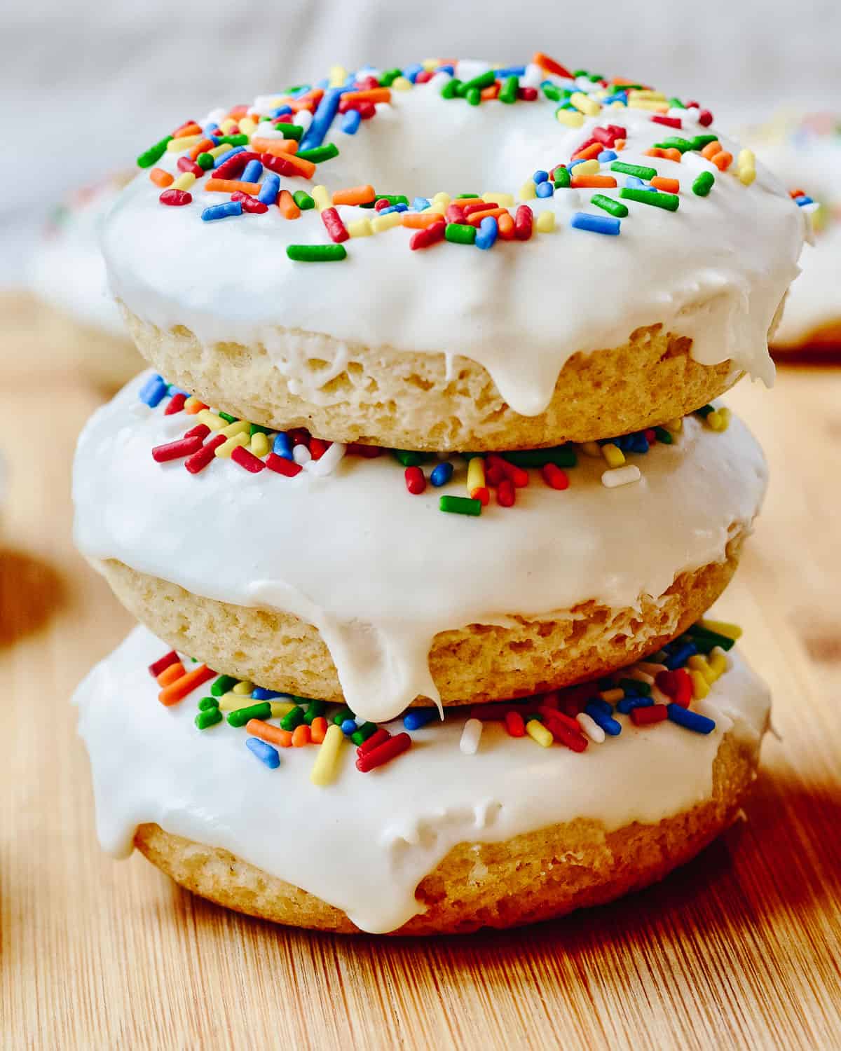Stacked vegan donuts with vanilla frosting stacked.