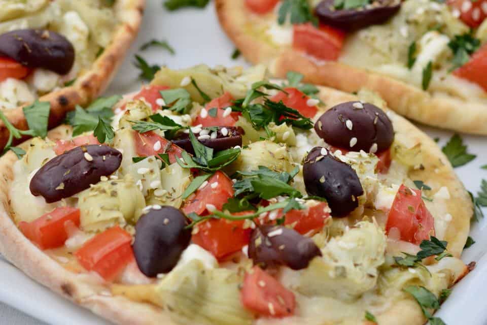 Easy Greek Pizza Recipe - Hummus, Feta, Tomatoes, Kalamata Olives, Artichoke Hearts, Fresh Parsley and Olive Oil.