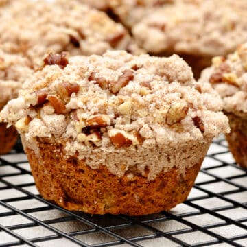 Single pear muffin with crumb topping sitting on cooling rack.