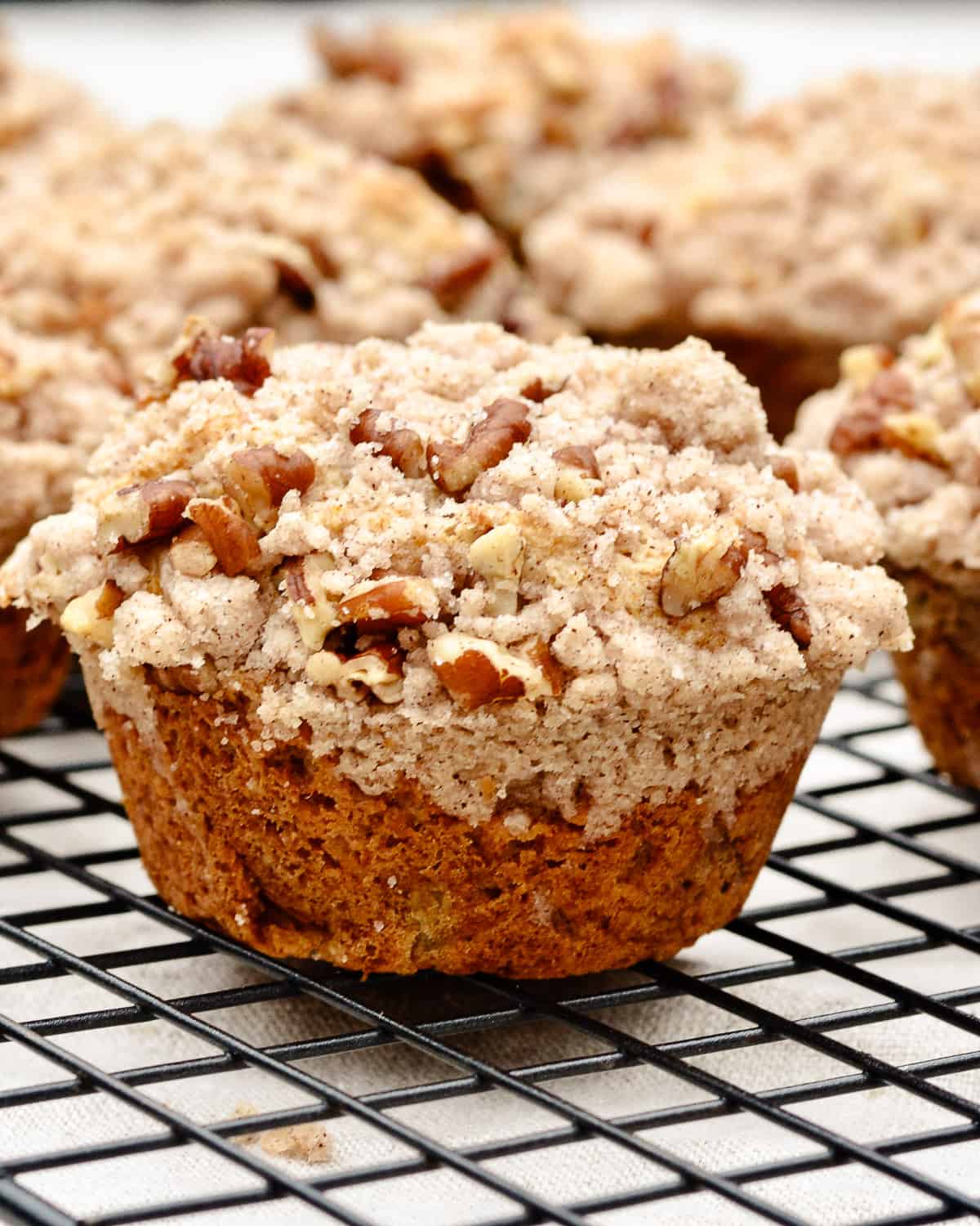 Single pear muffin with crumb topping sitting on cooling rack.
