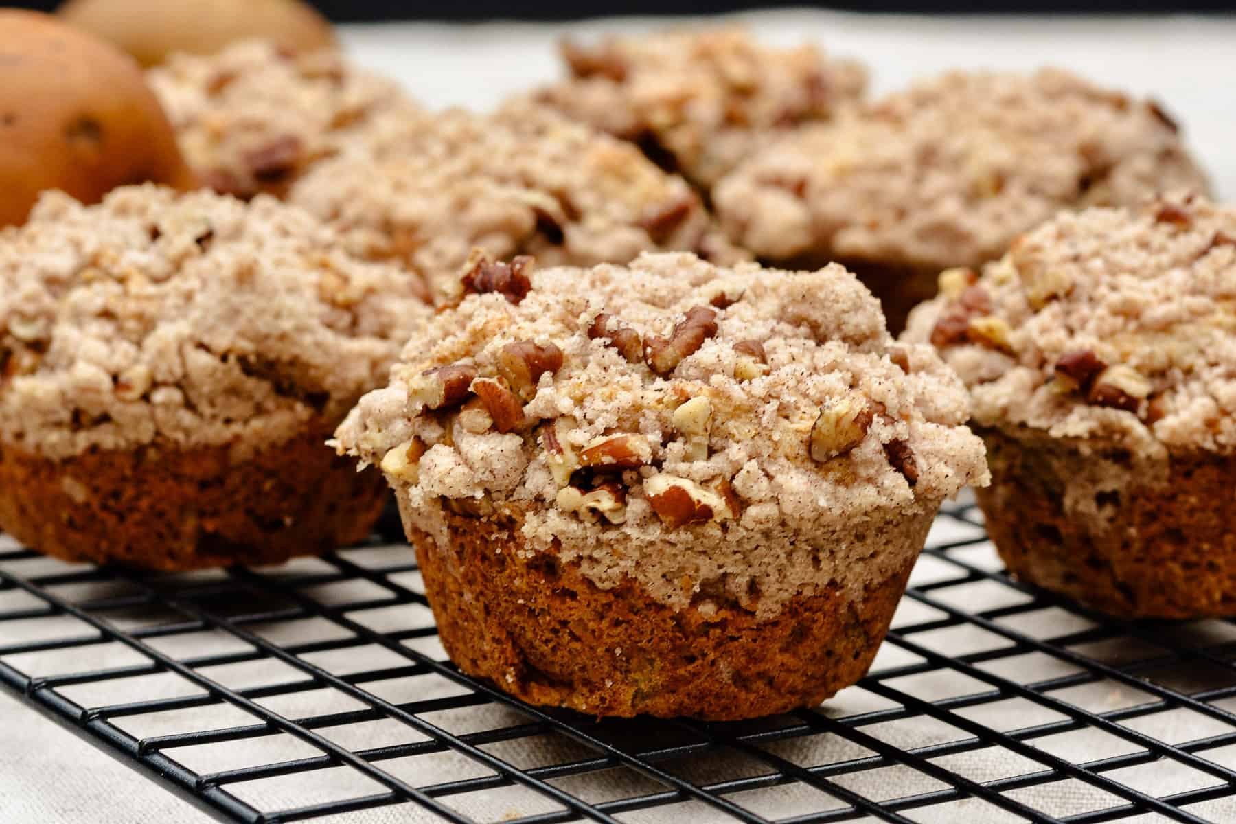 Group of pear muffins sitting on black cooling rack.