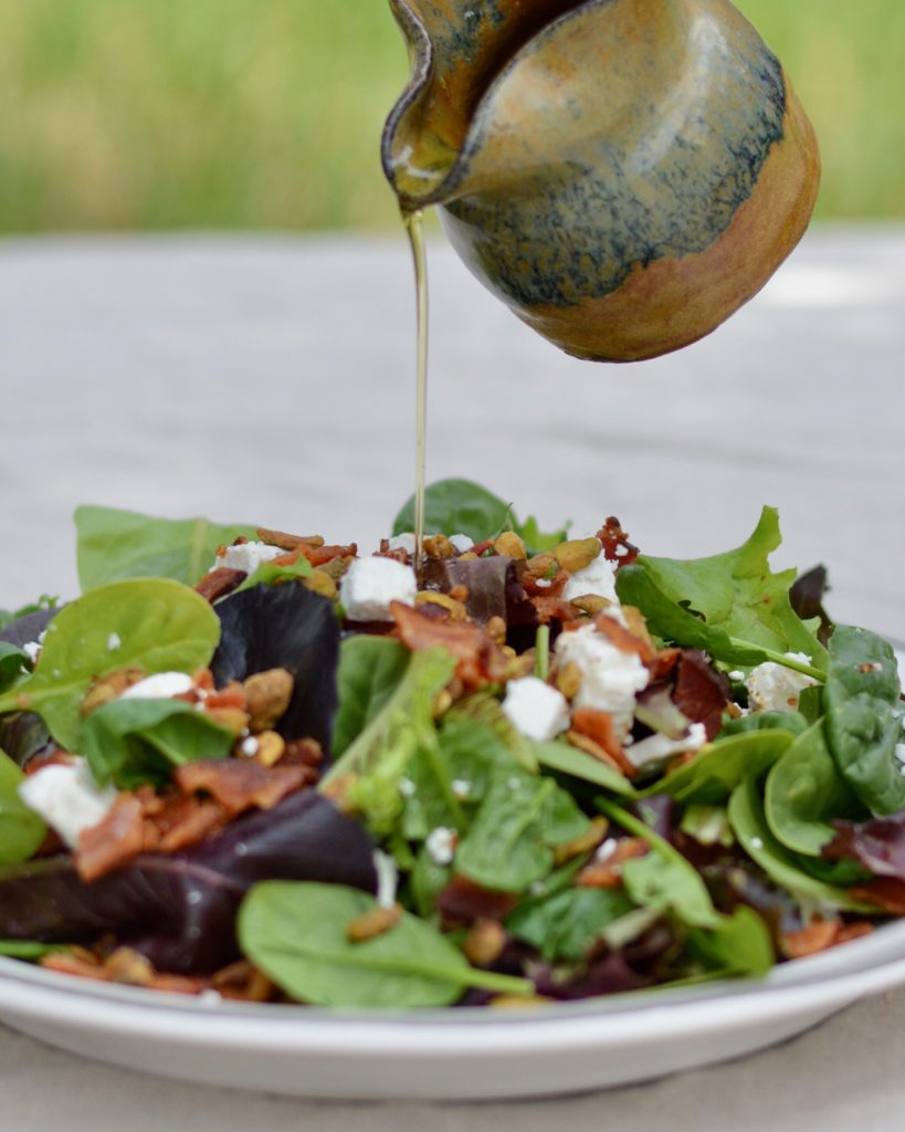 Italian Bacon Salad with warm homemade apricot dressing. Goat cheese, pistachios, bacon and spring mix salad.