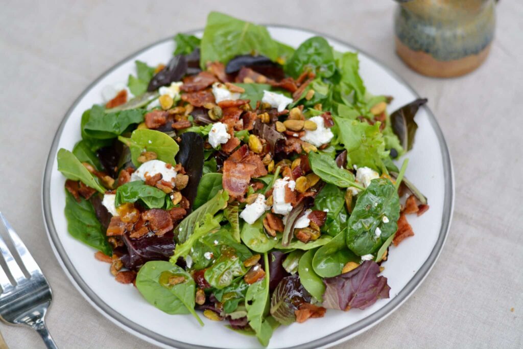 Italian Bacon Salad with warm homemade apricot dressing. Goat cheese, pistachios, bacon and spring mix salad.