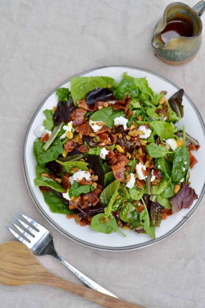 Italian Bacon Salad with warm homemade apricot dressing. Goat cheese, pistachios, bacon and spring mix salad.