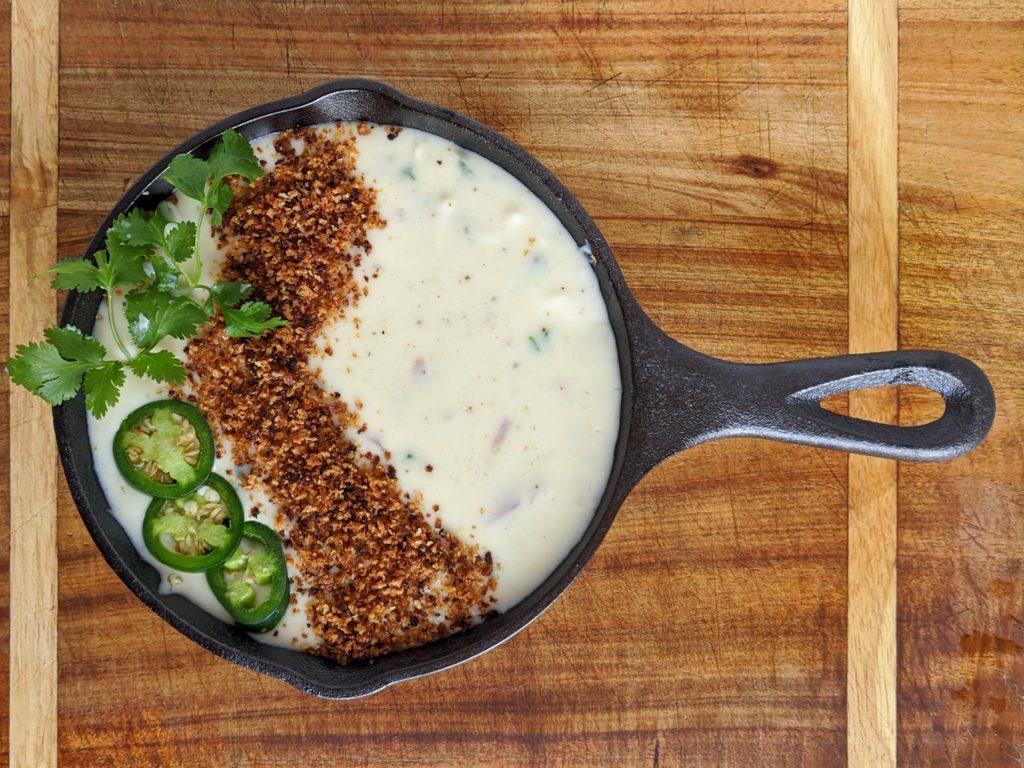 The BEST queso dip with jalapeño, red onion, monterey jack cheese. Topped with bread crumbs, jalapeños and cilantro. Seriously the most amazing queso ever.