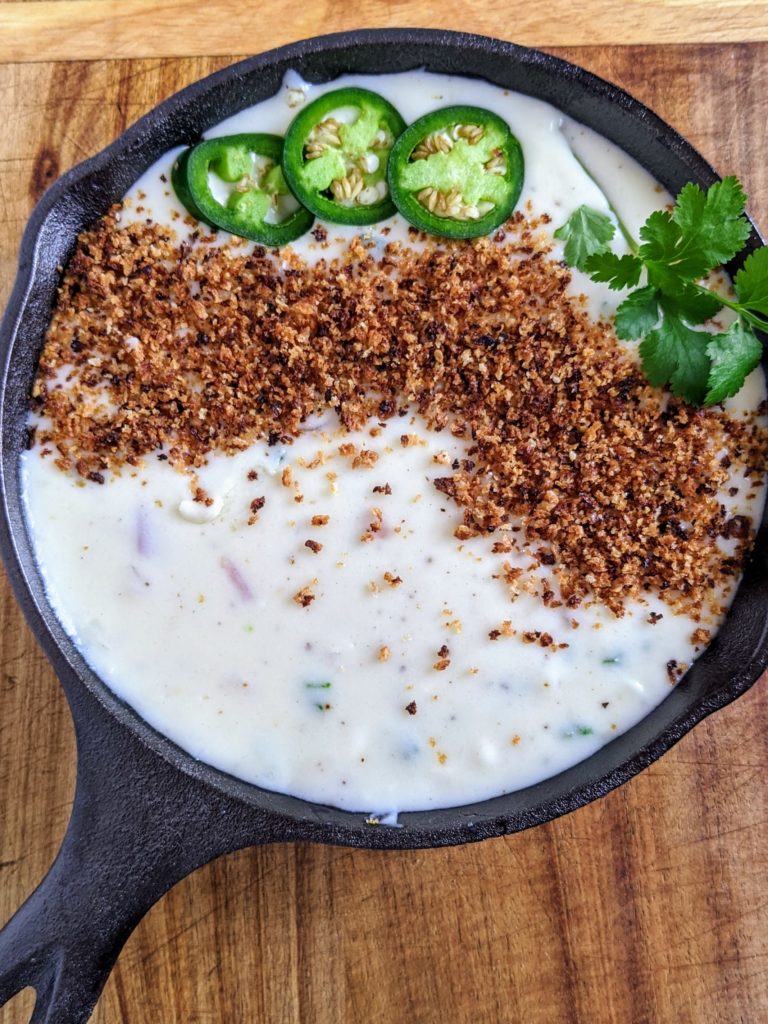 The BEST queso dip with jalapeño, red onion, monterey jack cheese. Topped with bread crumbs, jalapeños and cilantro. Seriously the most amazing queso ever.