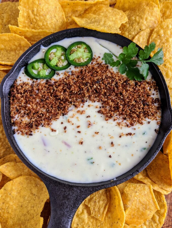 The BEST queso dip with jalapeño, red onion, monterey jack cheese. Topped with bread crumbs, jalapeños and cilantro. Seriously the most amazing queso ever.