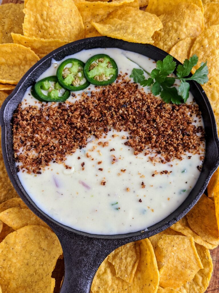 The BEST queso dip with jalapeño, red onion, monterey jack cheese. Topped with bread crumbs, jalapeños and cilantro. Seriously the most amazing queso ever.