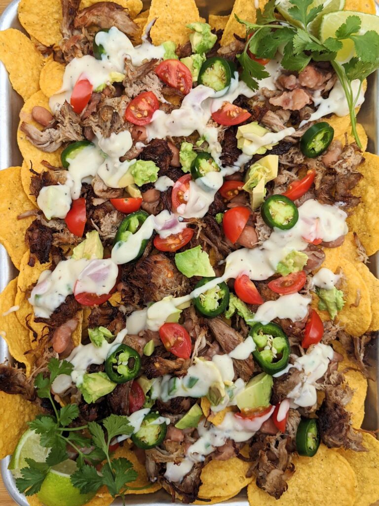 Carnitas burrito with queso, jalapeño pinto beans, and all the fixings! So delicious and easy to make ahead and freeze for another lunch or dinner.