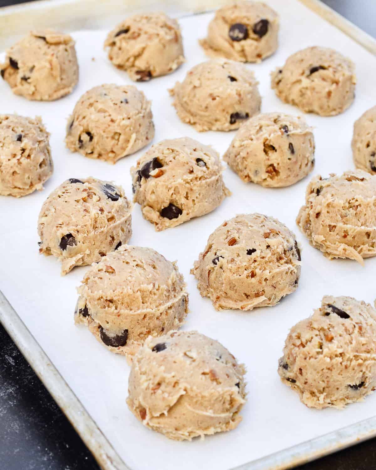 Balls of cookie dough on a lined baking sheet.