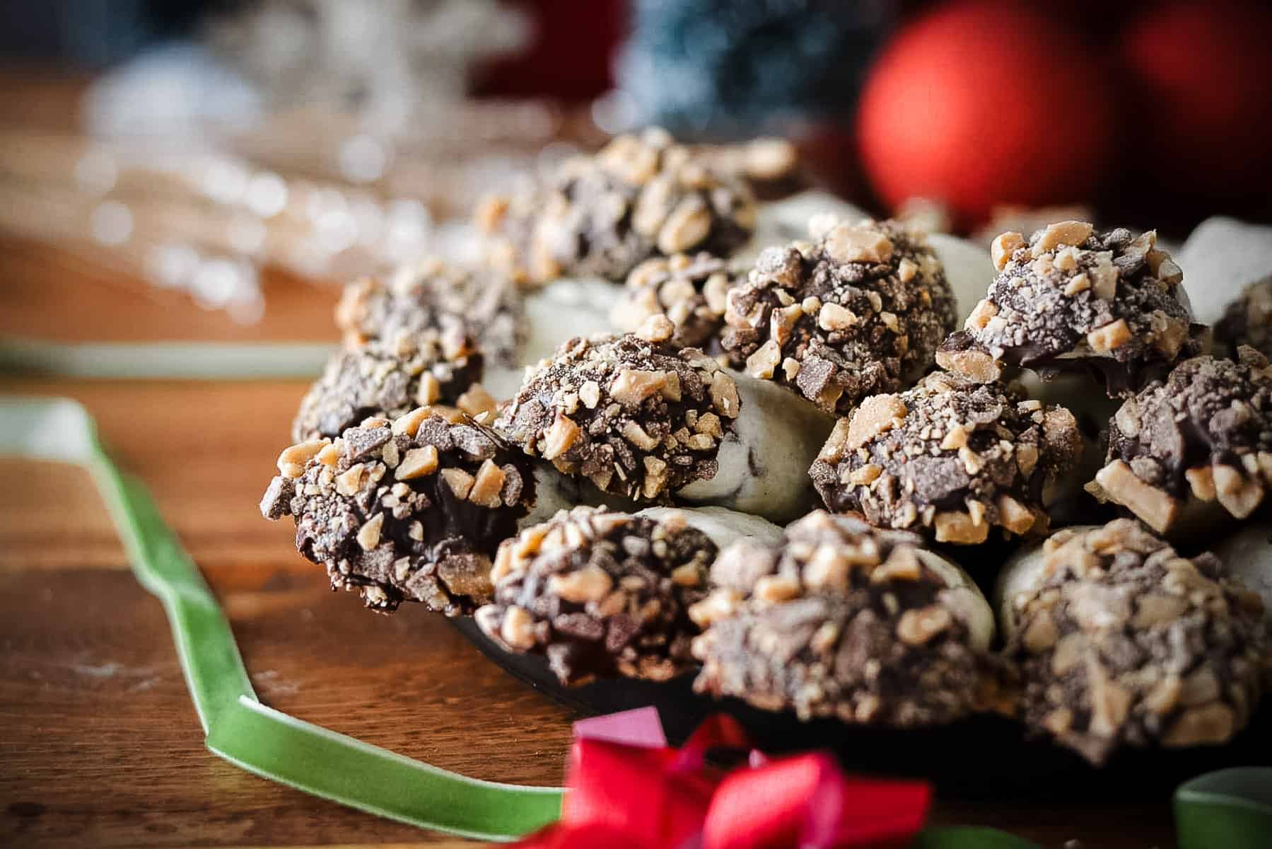 Cookies stacked on a plate with ribbon and christmas decoration around.