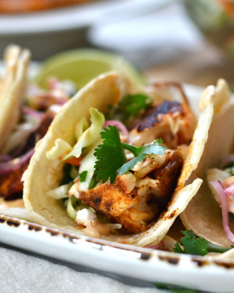 Super easy Blackened Fish Tacos with Tilapia, cilantro slaw and 2 ingredient sauce. Delicious taco night and summer meal.