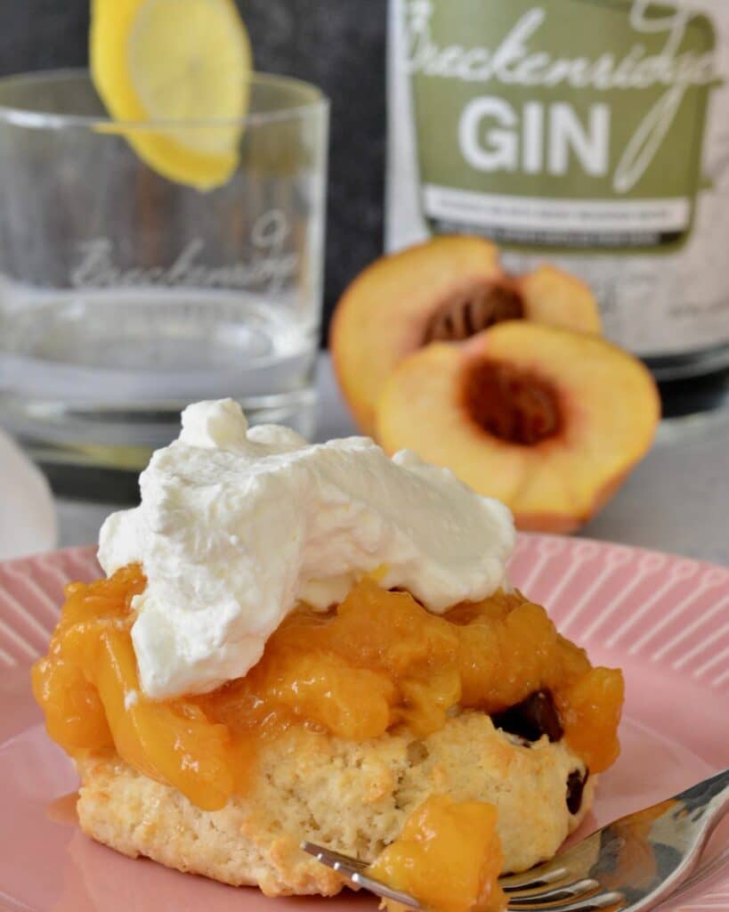 A twist on classic Peaches and Cream Shortbread with a splash of Breckenridge Gin. Tender and soft chocolate chip biscuits with homemade peach sauce and homemade whip cream. The BEST summer dessert!