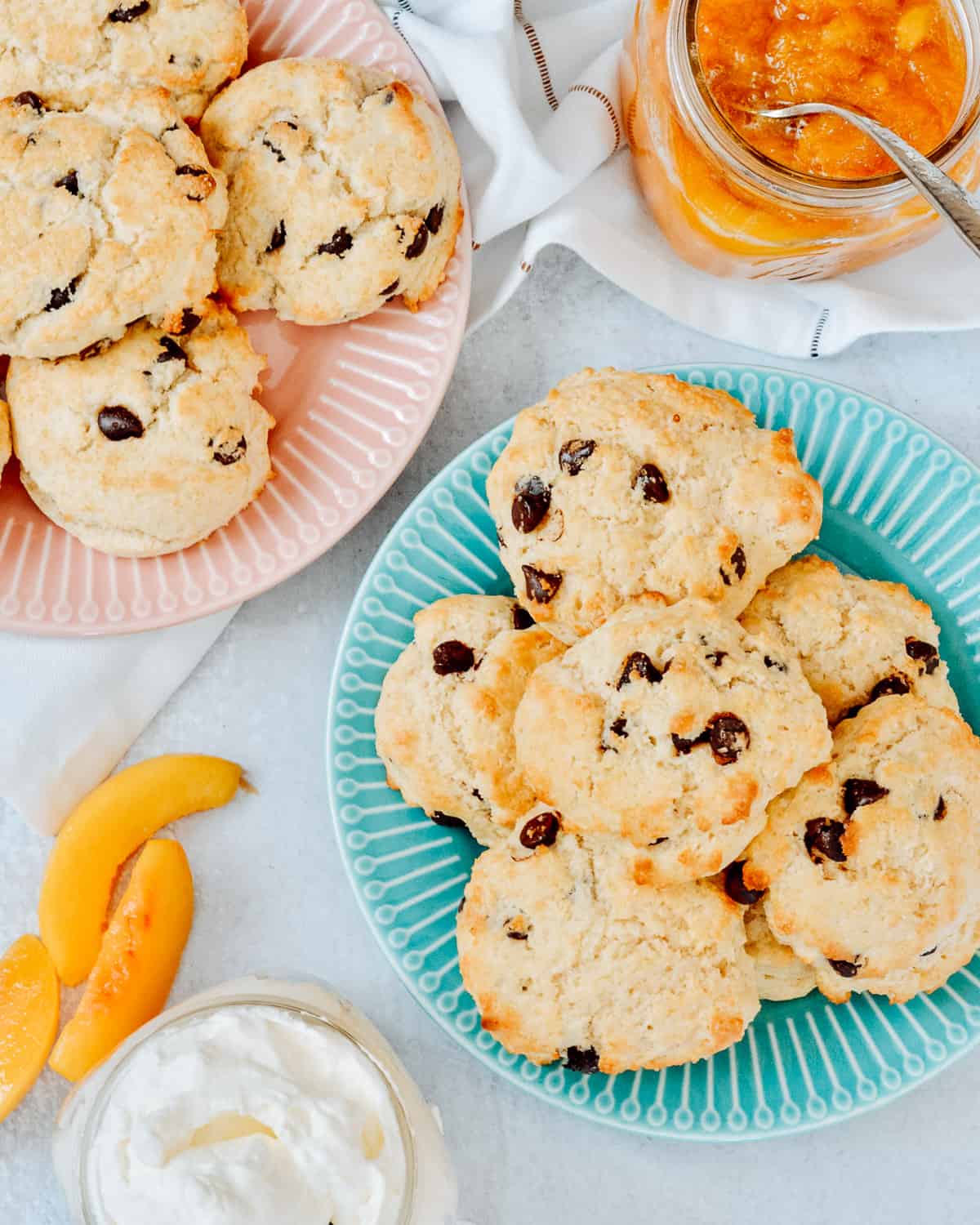 Plates full of chocolate chip shortcakes with fresh peaches and whip cream on table.