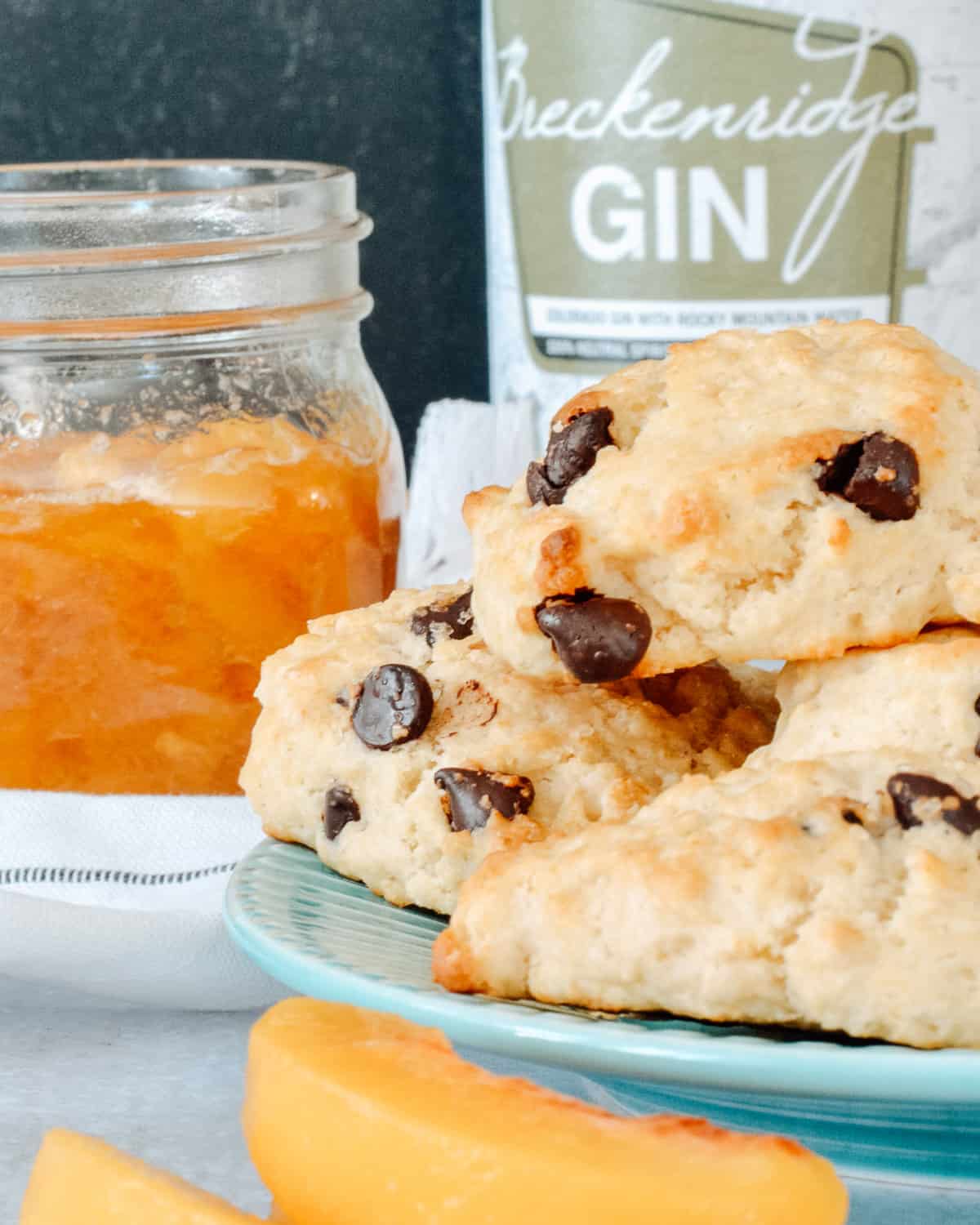 Plate of shortcakes with jar of peaches and Breckenridge Gin in background.