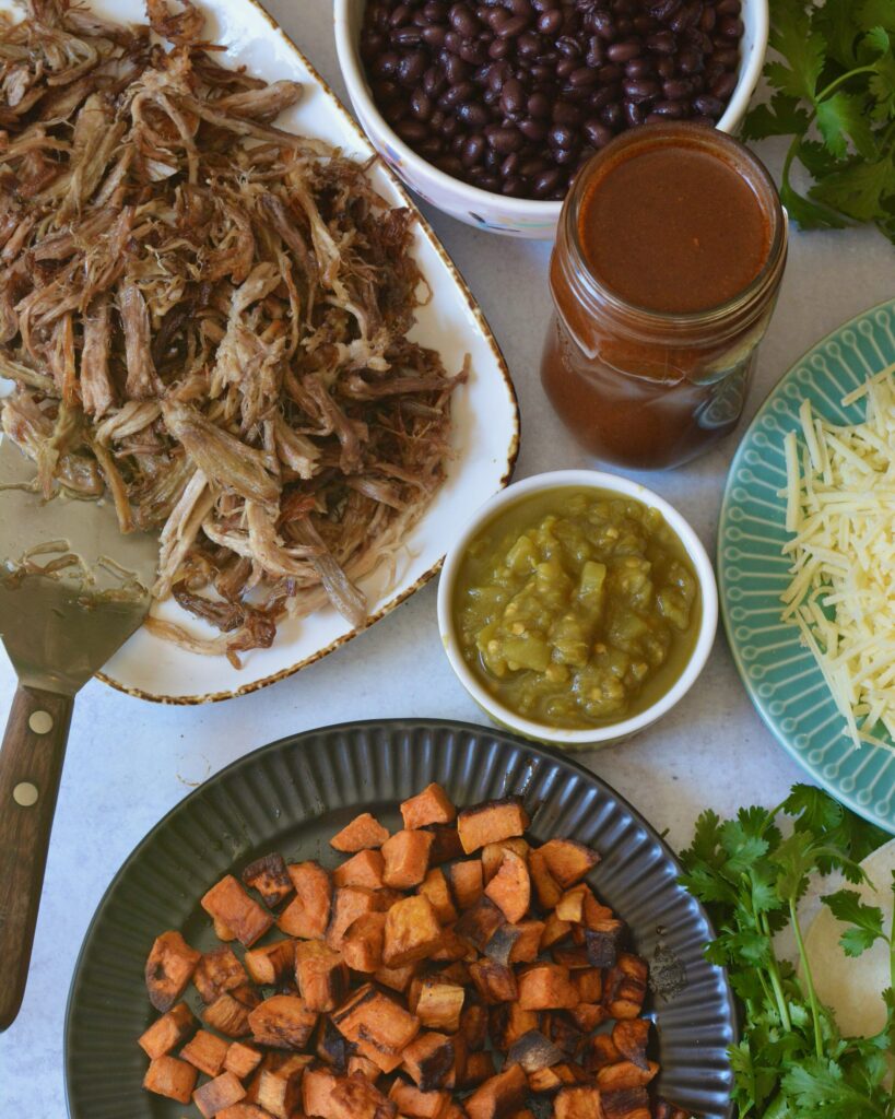 Delicious Make Ahead Enchiladas filled with Carnitas, Black Beans and Sweet Potatoes. Outstanding flavor combination of sweet, savory and spice. Simple homemade enchilada sauce recipe too!