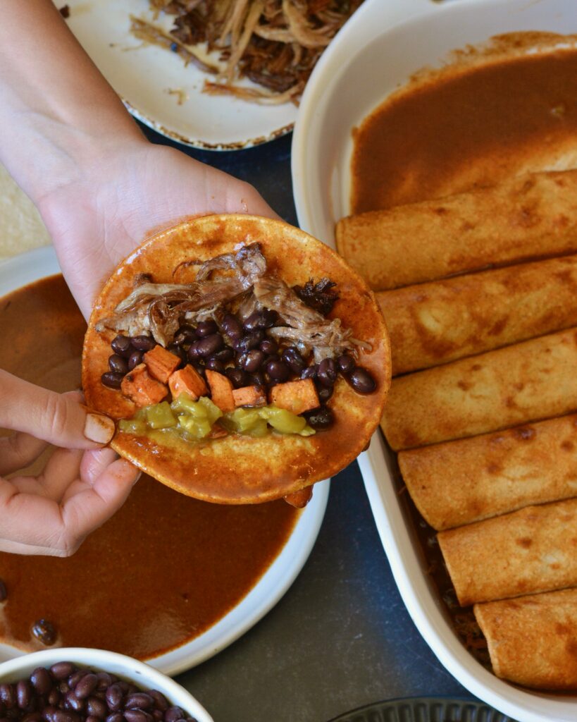 Delicious Make Ahead Enchiladas filled with Carnitas, Black Beans and Sweet Potatoes. Outstanding flavor combination of sweet, savory and spice. Simple homemade enchilada sauce recipe too!