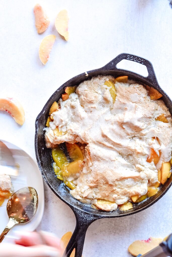 Cast Iron Peach Cobbler Perfection | Deliciously sweet fruit topped with a classic crisp biscuit topping. Add whip cream or ice cream and dig in! Perfect for parties.