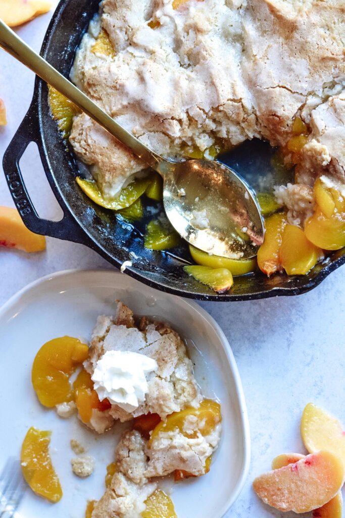 Cast Iron Peach Cobbler Perfection | Deliciously sweet fruit topped with a classic crisp biscuit topping. Add whip cream or ice cream and dig in! Perfect for parties.