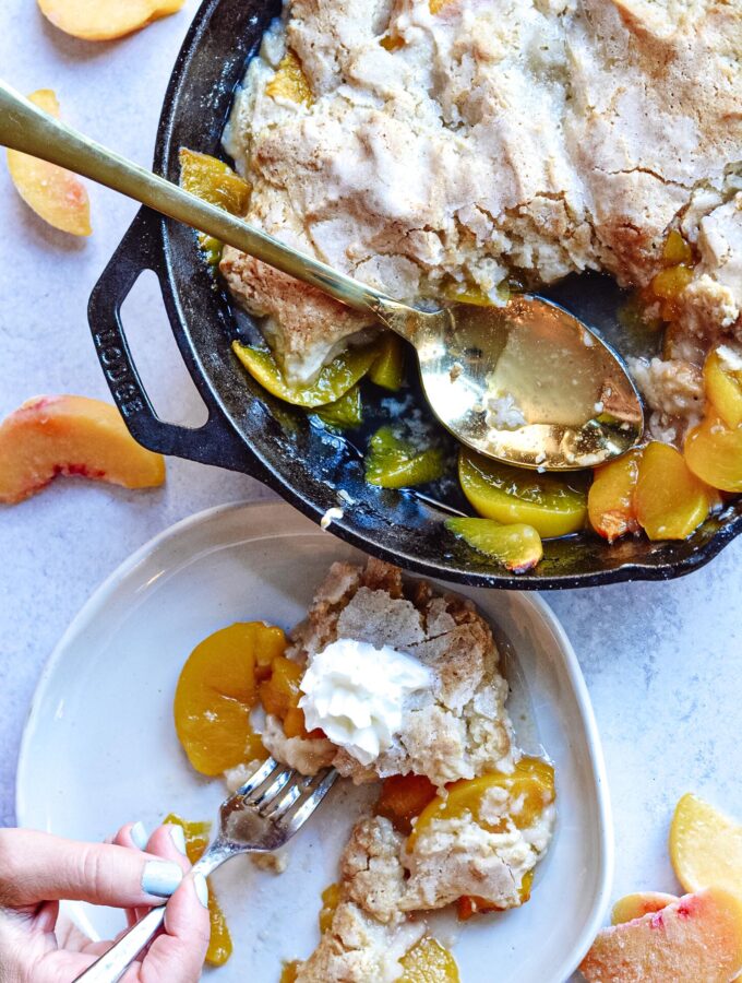 Cast Iron Peach Cobbler Perfection | Deliciously sweet fruit topped with a classic crisp biscuit topping. Add whip cream or ice cream and dig in! Perfect for parties.