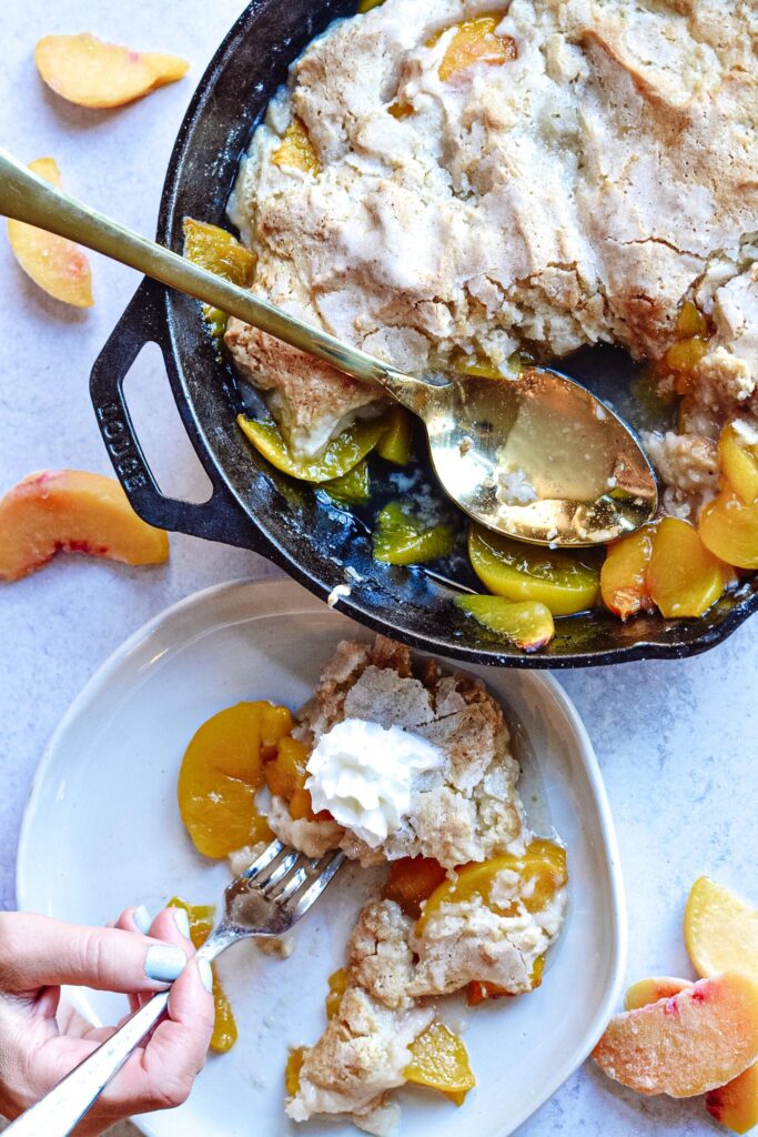 Cast Iron Peach Cobbler Perfection | Deliciously sweet fruit topped with a classic crisp biscuit topping. Add whip cream or ice cream and dig in! Perfect for parties.
