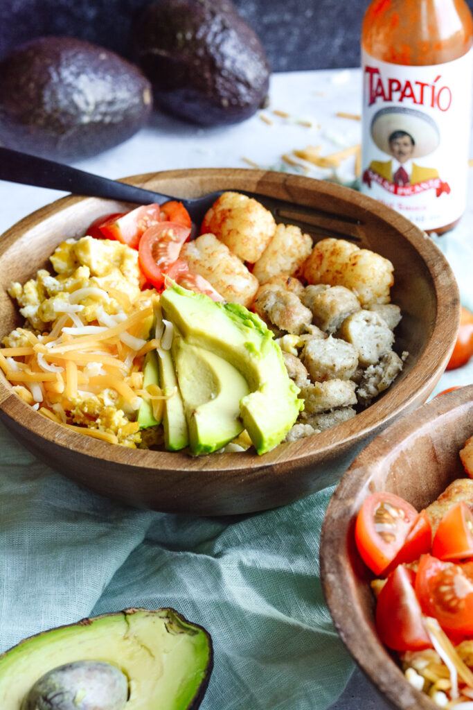 Protein Breakfast Bowl — Perfect brunch hash, scrambled eggs, tater tots, cheese, avocado, sausage and toppings.