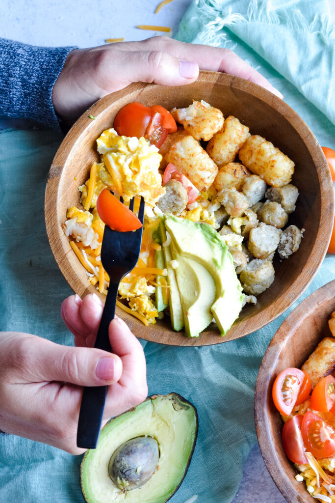 Protein Breakfast Bowl — Perfect brunch hash, scrambled eggs, tater tots, cheese, avocado, sausage and toppings.
