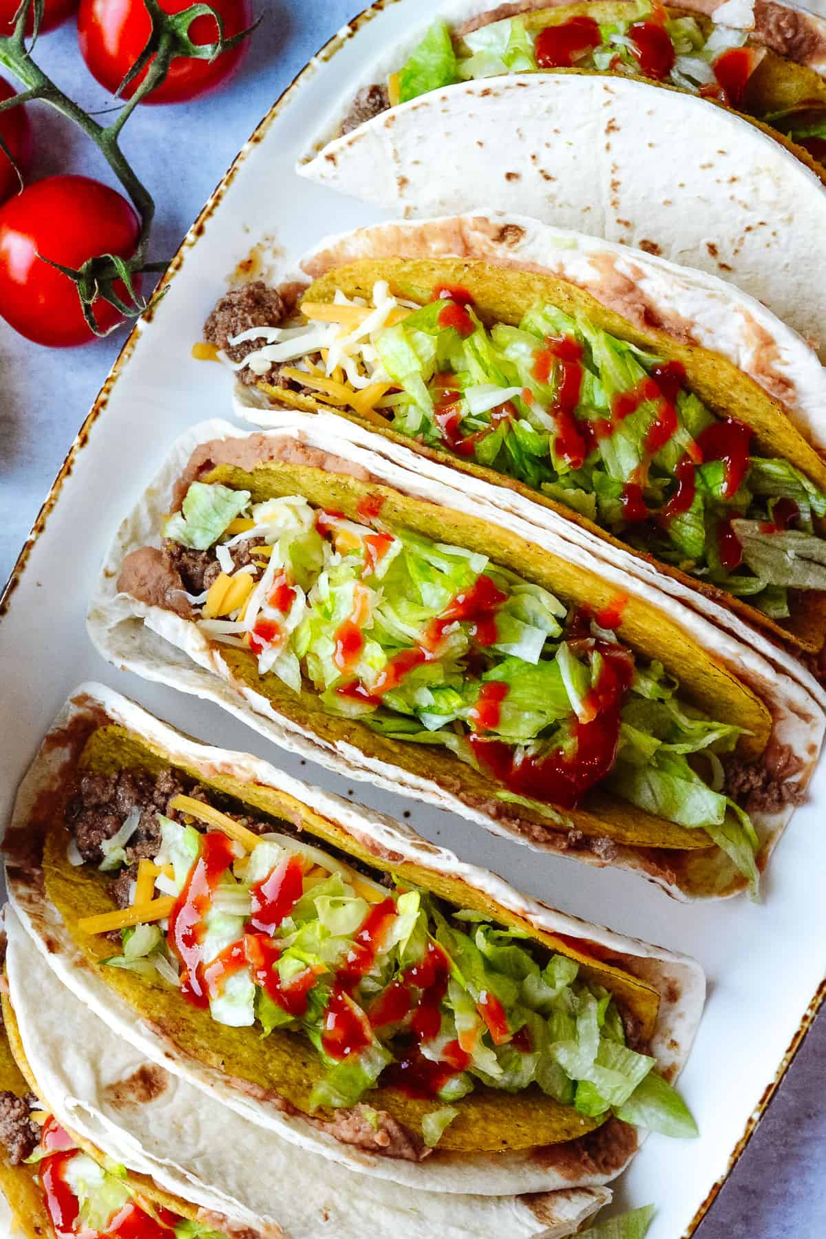 Tacos on a plate with hot sauce.