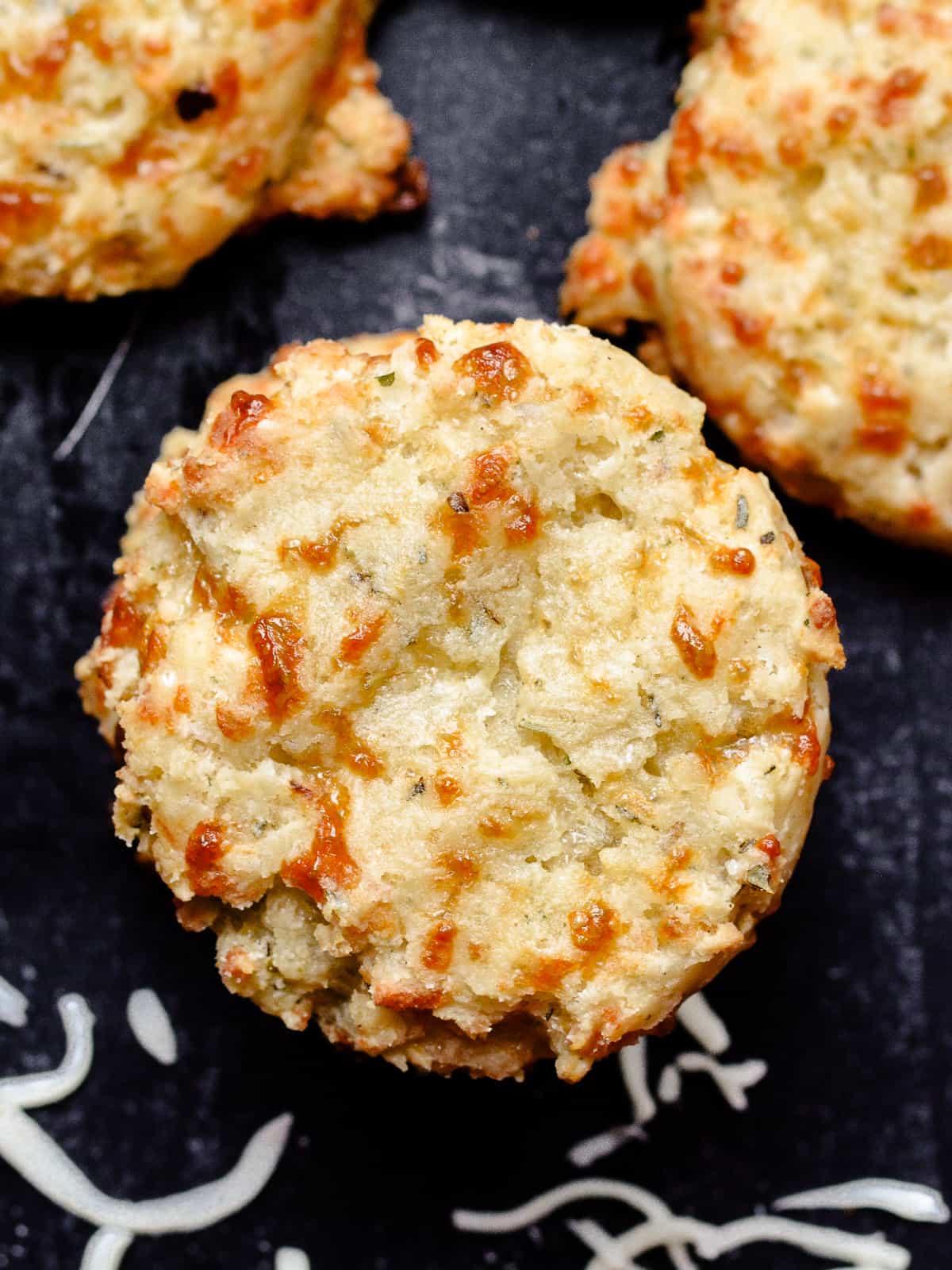 Up close of biscuit with black background and cheese shreds.