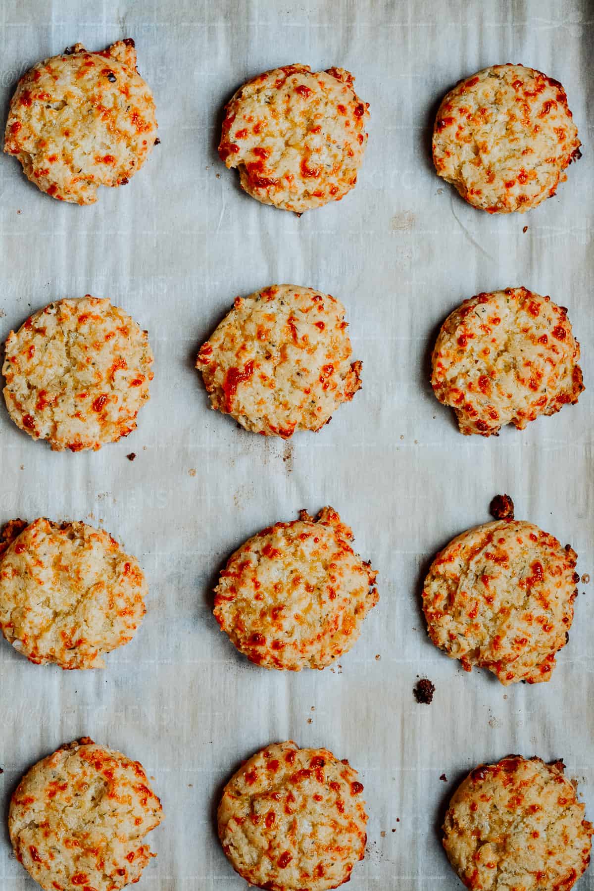 Fully baked Italian cheese and herb biscuits on a baking sheet.