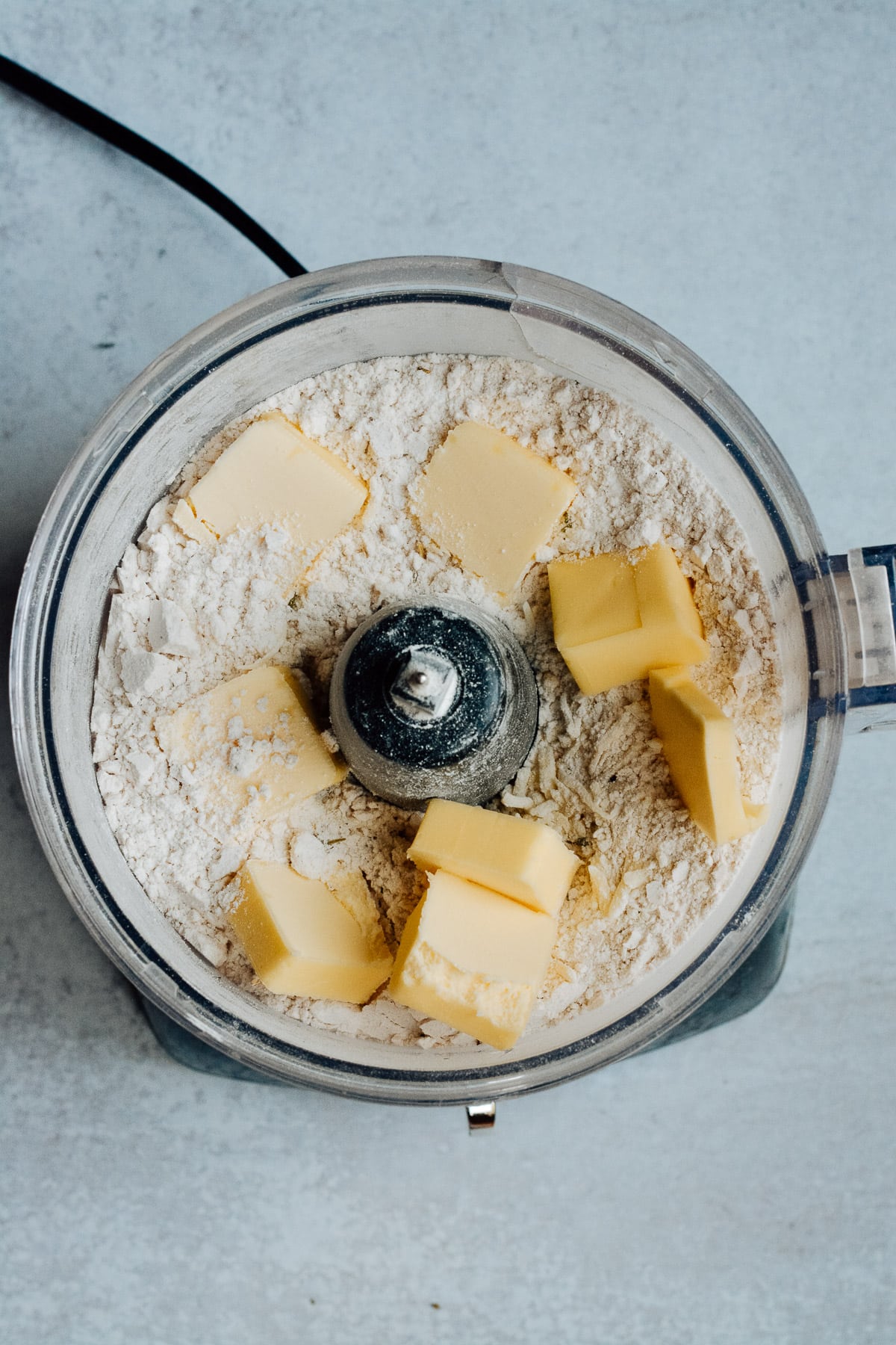 Butter added to flour mixture in food processor.