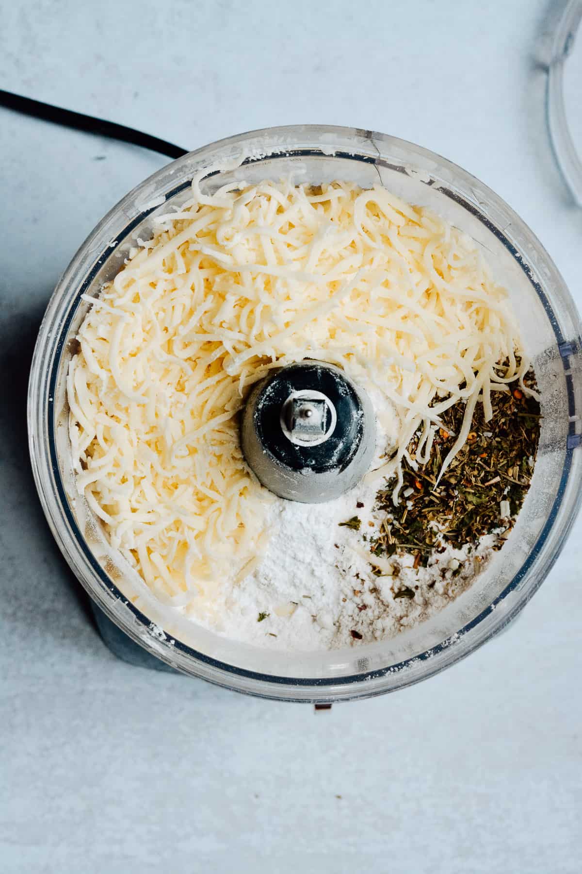 Flour, cheese and herbs in a food processor.