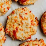 Italian cheese and herb biscuits on a baking sheet with parchment paper.