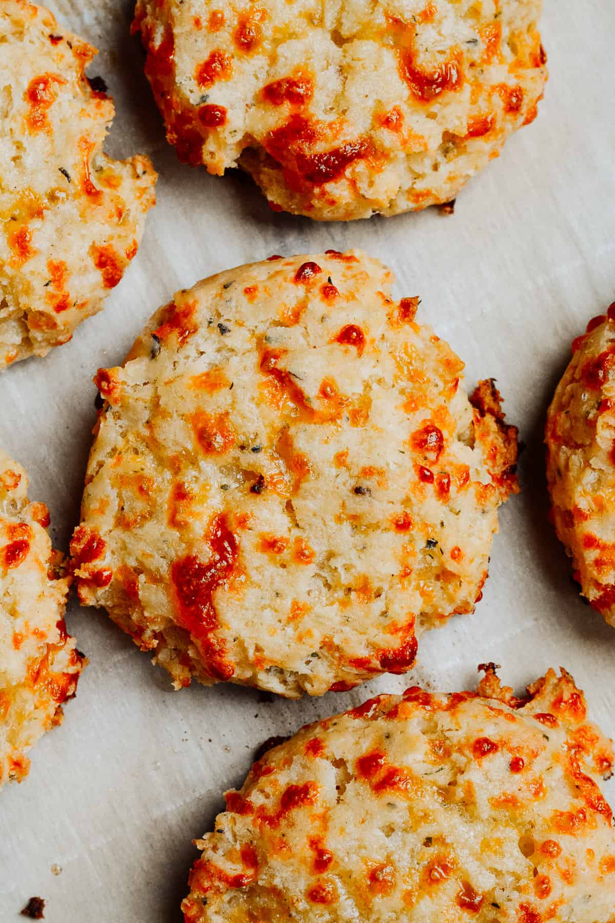 Italian cheese and herb biscuits on a baking sheet with parchment paper.