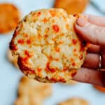 Hand holding an Italian biscuit with more biscuits in background.