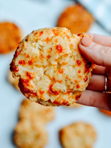 Hand holding an Italian biscuit with more biscuits in background.