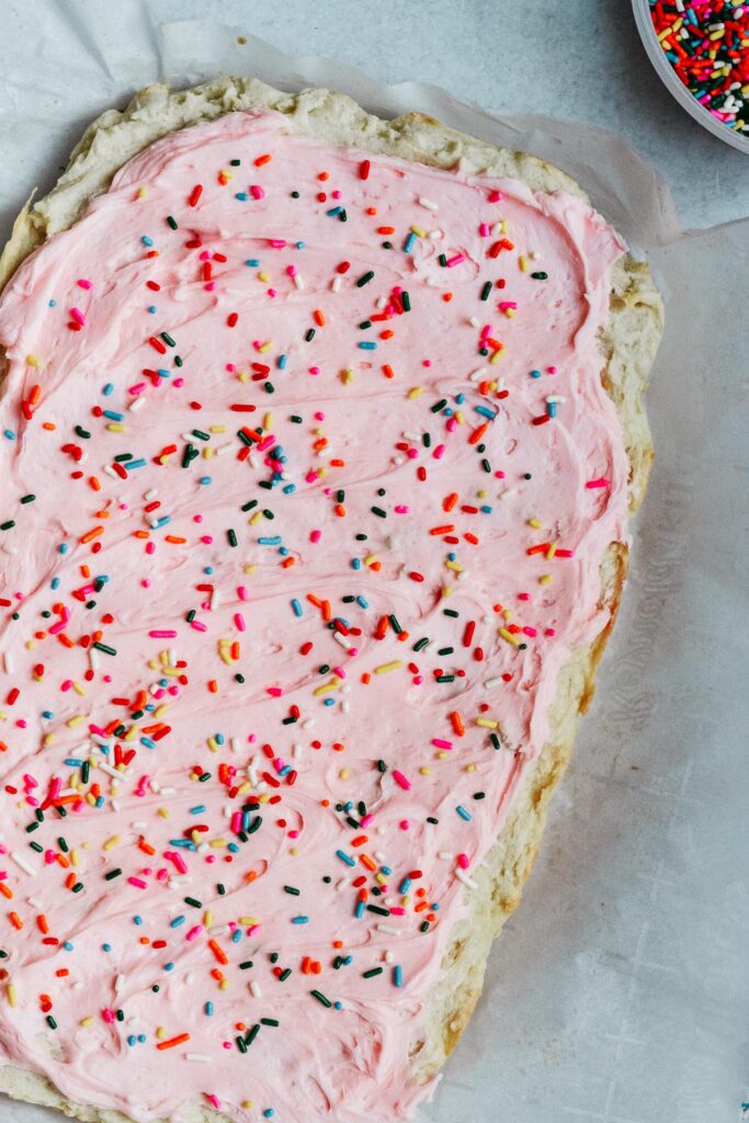 Soft and sweet with a delicate crumb, these Sugar Cookie Bars are made with a simple replacement gluten free flour. Topped with a not-too-sweet frosting and decorated with sprinkles. Kids and adults will love it! #sugarcookie #cookiebars #kidfriendly