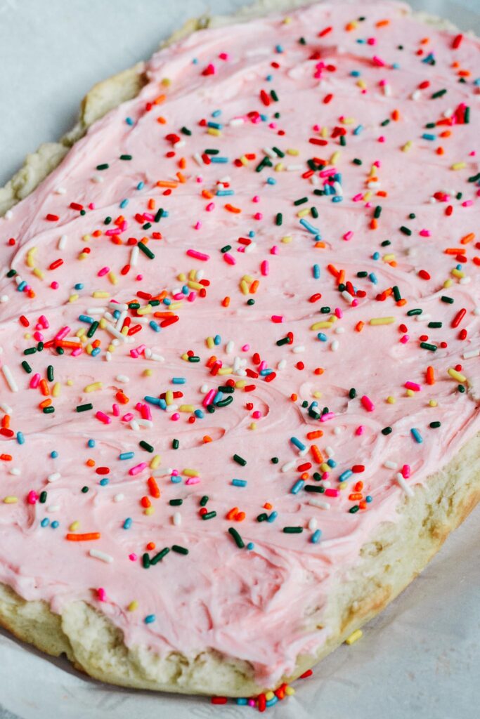 Soft and sweet with a delicate crumb, these Sugar Cookie Bars are made with a simple replacement gluten free flour. Topped with a not-too-sweet frosting and decorated with sprinkles. Kids and adults will love it! #sugarcookie #cookiebars #kidfriendly