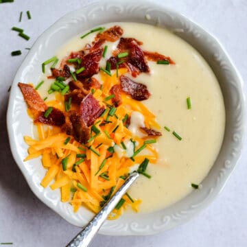 Up close Potato Soup with cheese, bacon and chives on top.