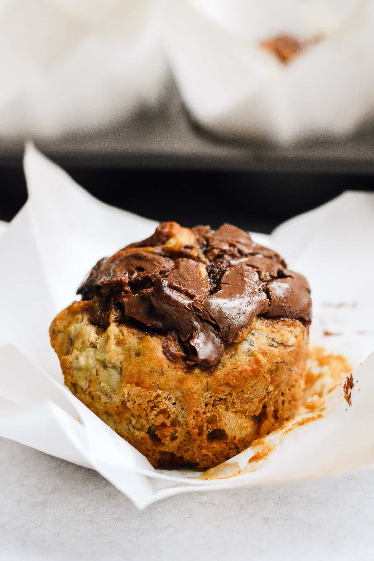 Close up of one nutella banana muffin with muffin tin in background.